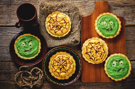 tartlet with pumkin and spinach cream for Halloween in the form of a monster for kids on a dark wood background. toning. selective focus on the middle tarts on the Boardの写真素材