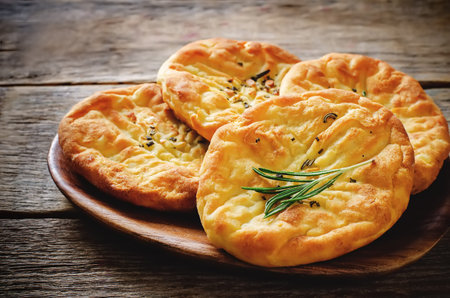 potato flatbread with rosemary on a dark wood background. toning. selective focus on rosemary on the...