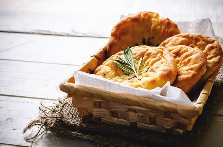 potato flatbread with rosemary on a dark wood background. toning. selective focus on rosemary on the round cakeの写真素材
