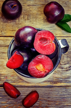 plums on a dark wood background. toning. selective focus on plum with a stone.の写真素材