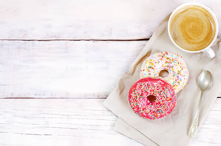 Donuts and coffee on a white wood background. toning. selective focus on red donutの写真素材
