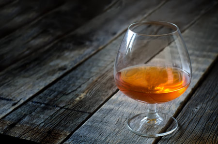 Glass of cognac on a wood background. the focus is on the left edge of the glass. toning