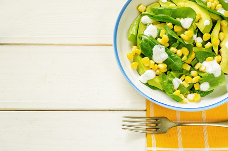 salad with corn, spinach and avocado on a white wood background. tinting. selective focus on the middle of the saladの写真素材