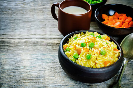 Indian vegetarian pilaf, Biriyani, with carrots and green peas on a dark wood background. tinting. selective focus on the middle pilafの写真素材