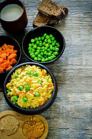 Indian vegetarian pilaf, Biriyani, with carrots and green peas on a dark wood background. tinting. selective focus on the middle pilafの写真素材