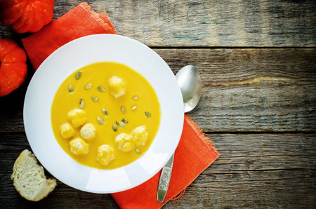 pumpkin soup with meatballs on a dark wood background. tinting. selective focus on the middle of the soupの写真素材