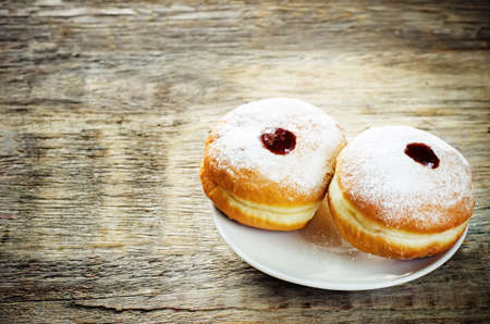 fresh doughnuts with jam on a dark wood background for Hanukkah. tinting. selective focus on the right donutの写真素材