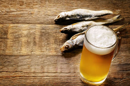 beer and fish vobla on a dark wood background. tinting. selective focus on beerの写真素材