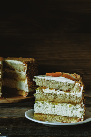 cake with almonds, cream, cheesecake and caramelised mango on a dark wood の写真素材