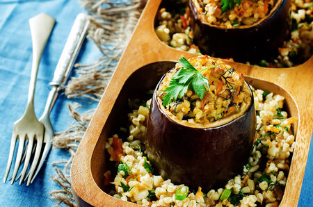 eggplant stuffed with bulgur and vegetables on a blue . tinting. selective focus on the parsleyの写真素材