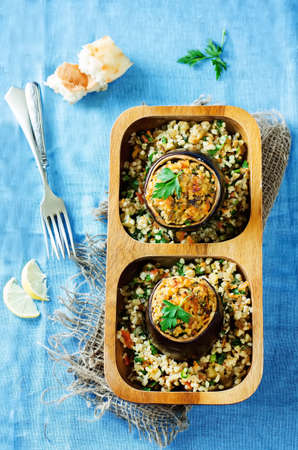 eggplant stuffed with bulgur and vegetables on a blue . tinting. selective focus on the parsley on the top eggplantの写真素材