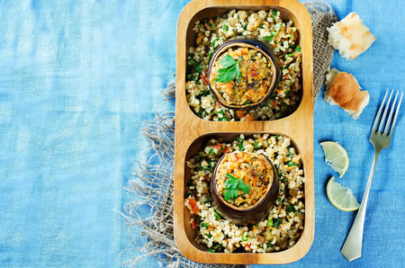 eggplant stuffed with bulgur and vegetables on a blue . tinting. selective focus on the parsley on the top eggplantの写真素材