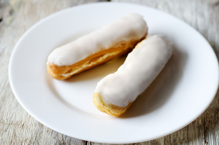 eclairs on a white plate on a light background of woodの写真素材