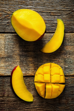mango on a dark wood background. tinting. selective focus on the mangos slicesの写真素材