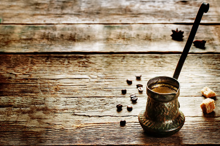 black coffee in the cezve on a dark wood background. tinting. selective focus on coffeeの写真素材