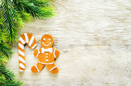 ginger biscuits and a branches of a Christmas tree on a white wood background. tinting. selective...
