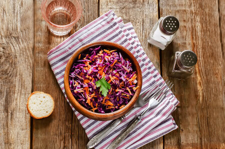 salad with carrots and red cabbage on a dark wood background. tinting. selective focus on parsleyの写真素材