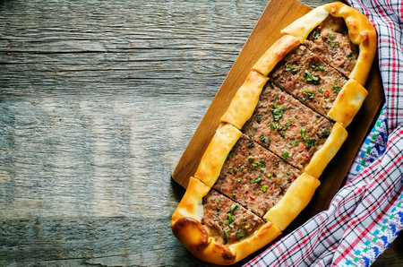 traditional Turkish pastries with meat on a dark wood background. pide. tinting. selective focus on...