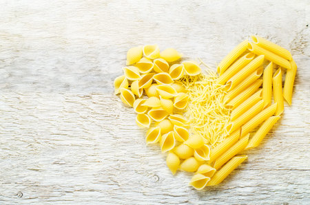 pasta in the form of hearts on the white wood background. tinting. selective focusの写真素材