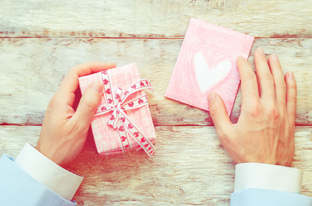 male hand holding card and gift. Valentine's day. tinting in retro vintage style. selective focusの写真素材