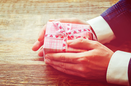 male hand holding a gift. Valentine's day. tinting in retro vintage style. selective focusの写真素材