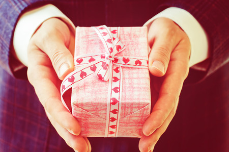 male hand holding a gift. Valentine's day. tinting in retro vintage style. selective focusの写真素材
