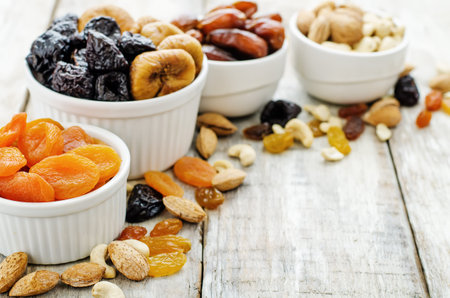mix of dried fruits and nuts on a white wood background. tinting. selective focus