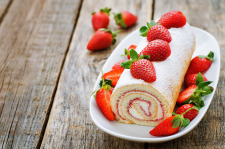cake roll with strawberries and cream cheese on a dark wood background. tinting. selective focusの写真素材