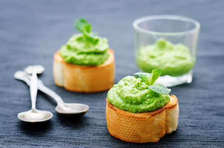 bruschetta with green peas and mint puree on a black background. tinting. selective focusの写真素材