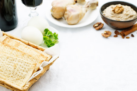 Matzah, wine, eggs, chicken, greens and haroset on a white background, traditional food for the...