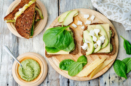 grilled rye sandwiches with cheese, spinach, pesto, avocado and goat cheeseの写真素材