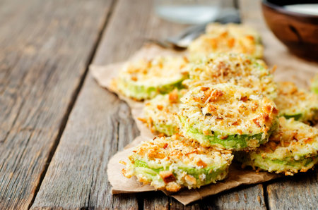 baked parmesan zucchini crisps on a dark wood background. the toning. selective focusの写真素材