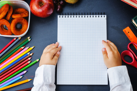 child hands holding notebook on a blackboardの写真素材