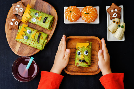 childrens hands holding plate with lunch in the form of monsters for Halloween. the toning. selective focusの写真素材