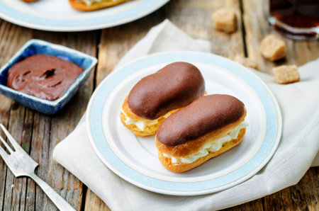 eclairs with cheese cream and chocolate glaze on a dark wood background