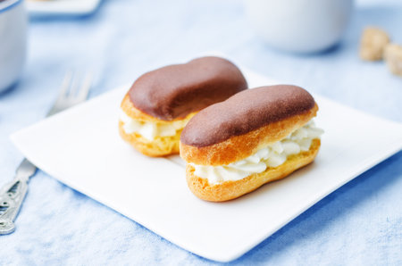 eclairs with cheese cream and chocolate glaze on a blue background
