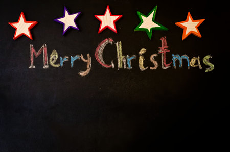 Merry Christmas written with chalk on a black background with wooden toys. the toning. selective focusの写真素材