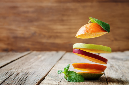 flying slices of fruit: apple, pear, orange on a dark wood background. toning. selective Focusの写真素材