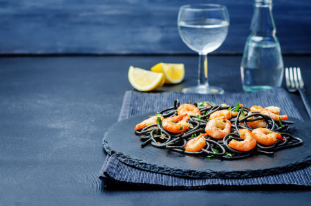 Black pasta with shrimps on a black background. toning. selective focusの写真素材