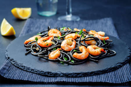 Black pasta with shrimps on a black background. toning. selective focusの写真素材