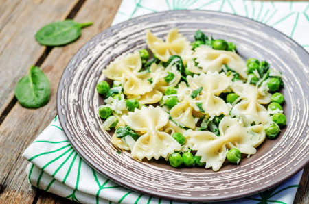 Spinach green peas Farfalle on dark wood background. toning. selective focusの写真素材