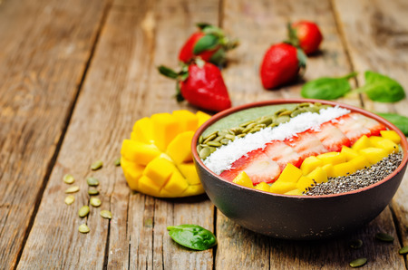 Spinach smoothie bowl with strawberries, coconut, mango, pumpkin seeds and seeds Chia. toning. selective focusの写真素材