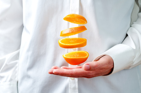 Men's hands hold the flying pieces of orange. toning. selective focusの写真素材