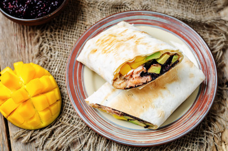 Salmon avocado mango black rice burritos. toning. selective focus