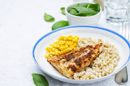 spices Cod with brown rice, spinach and corn. toning. selective focusの写真素材