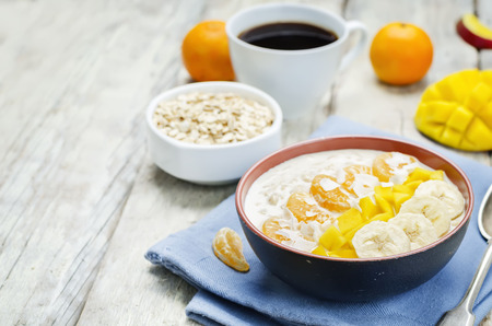 Oatmeal with mango, banana, tangerine oranges and coconut flakes. toning. selective focusの写真素材