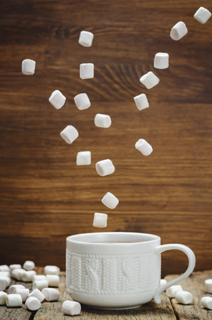 Cup of cocoa with flying marshmallows on the wood background. toning. selective focusの写真素材