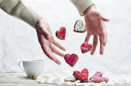 Male hand with flying cookies in the forms of hearts. toning. selective focusの写真素材
