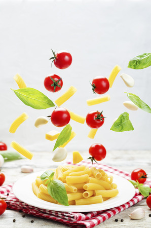 Flying pasta with tomatoes; garlic; cheese and basil. toning. selective focusの写真素材
