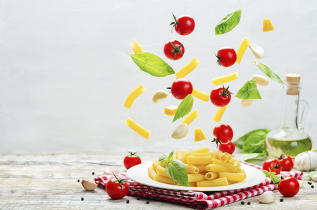 Flying pasta with tomatoes; garlic; cheese and basil. toning. selective focusの写真素材